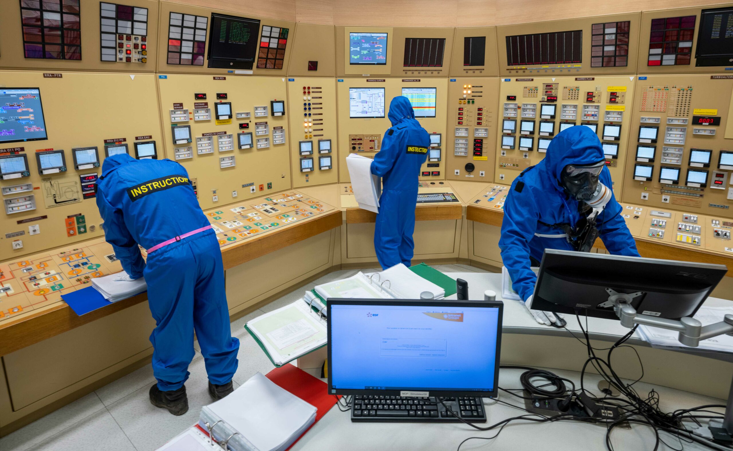 Personnel en combinaison de protection dans la salle de contrôle d'une centrale nucléaire